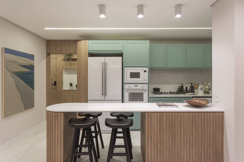 cozinha americana com cores claras e mesa dividindo ambientes