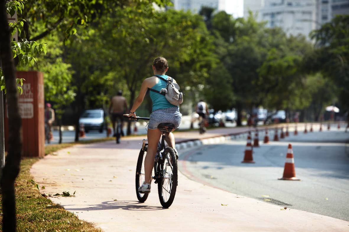 mulher andando de bicicleta pela ciclovia de um bairro de são paulo