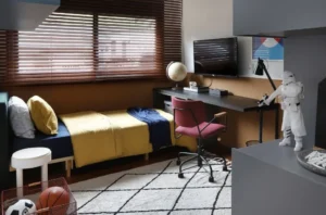 A imagem mostra um quarto de solteiro ou infantil bem decorado, que combina as funções de dormir e estudar/trabalhar em casa.