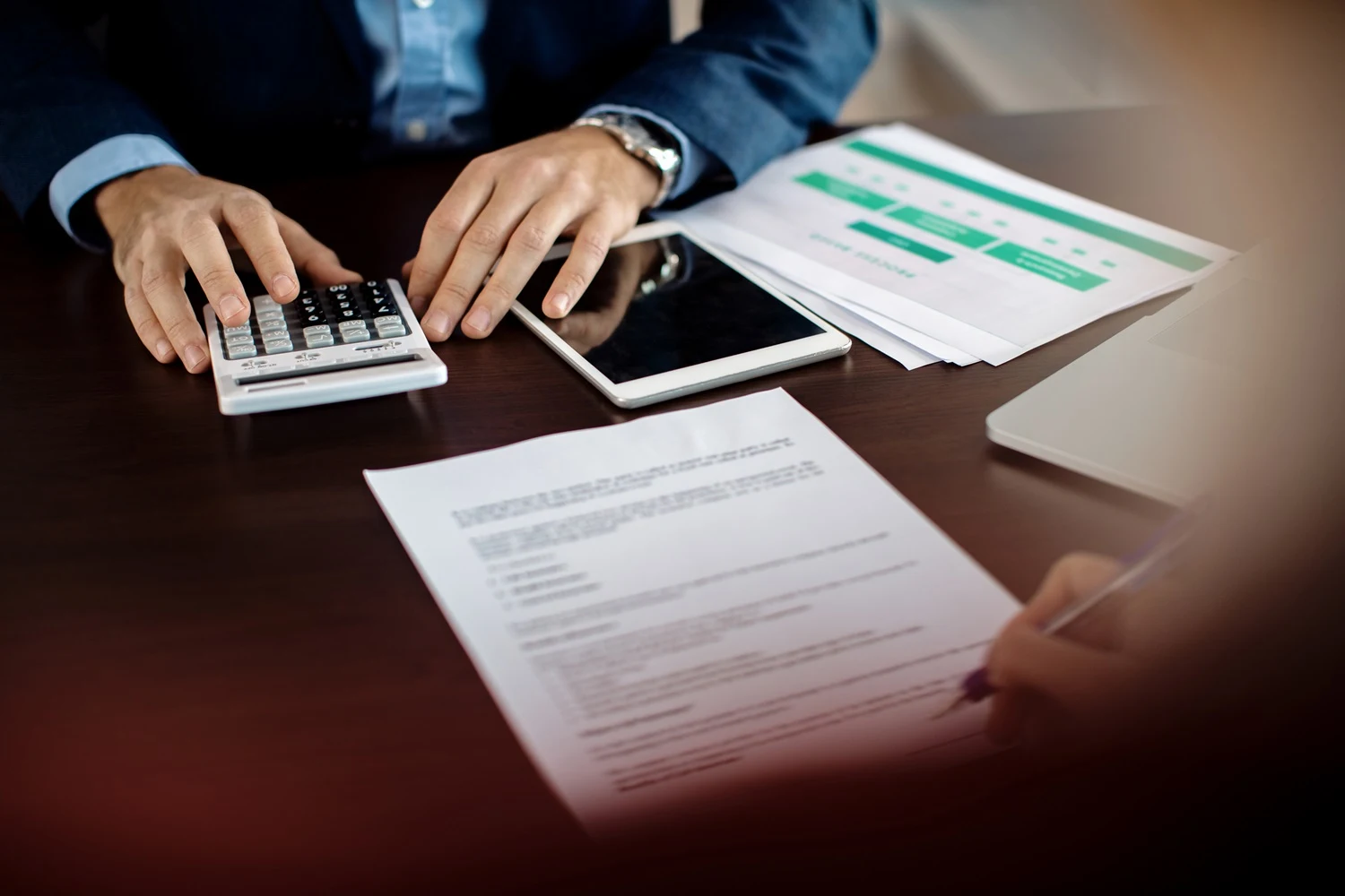 A imagem mostra pessoas envolvidas em atividades financeiras ou contábeis, como o cálculo e a assinatura de documentos.