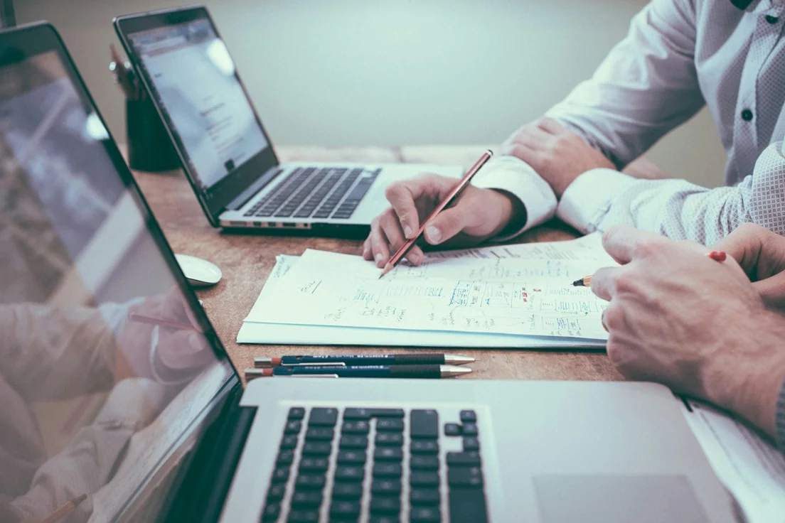 pessoas olhando para notebook com caderno de anotações