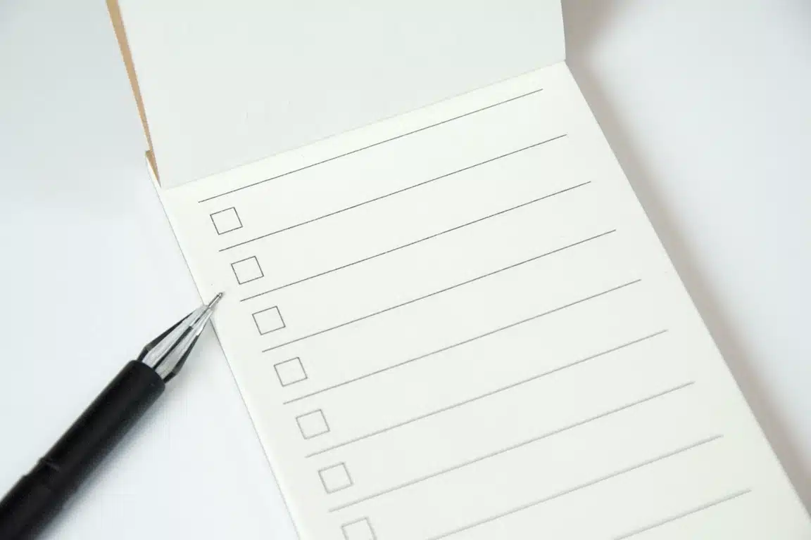 A imagem mostra um bloco de notas com uma lista de verificação (checklist) em branco e uma caneta.