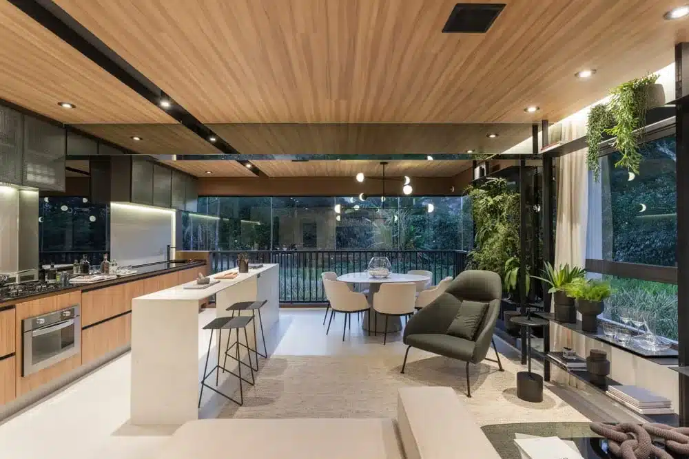 A imagem mostra uma cozinha e sala de estar integradas com um design de interiores moderno e acabamentos em madeira, típicos de apartamentos contemporâneos.