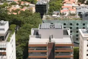 A imagem mostra uma vista aérea de edifícios residenciais e comerciais em uma área urbana densamente arborizada