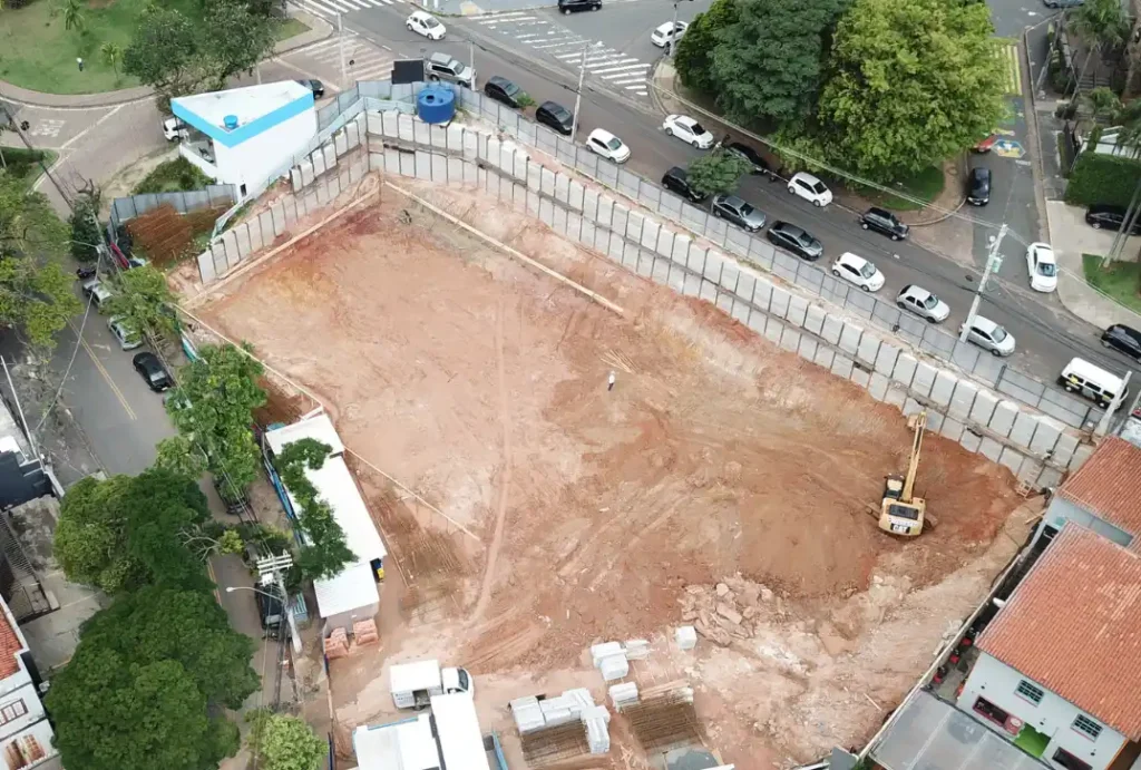 A imagem mostra uma obra de construção civil em estágio inicial de fundação. 