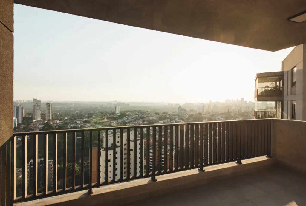 A imagem mostra a varanda de um apartamento com vista para a cidade de São Paulo. 